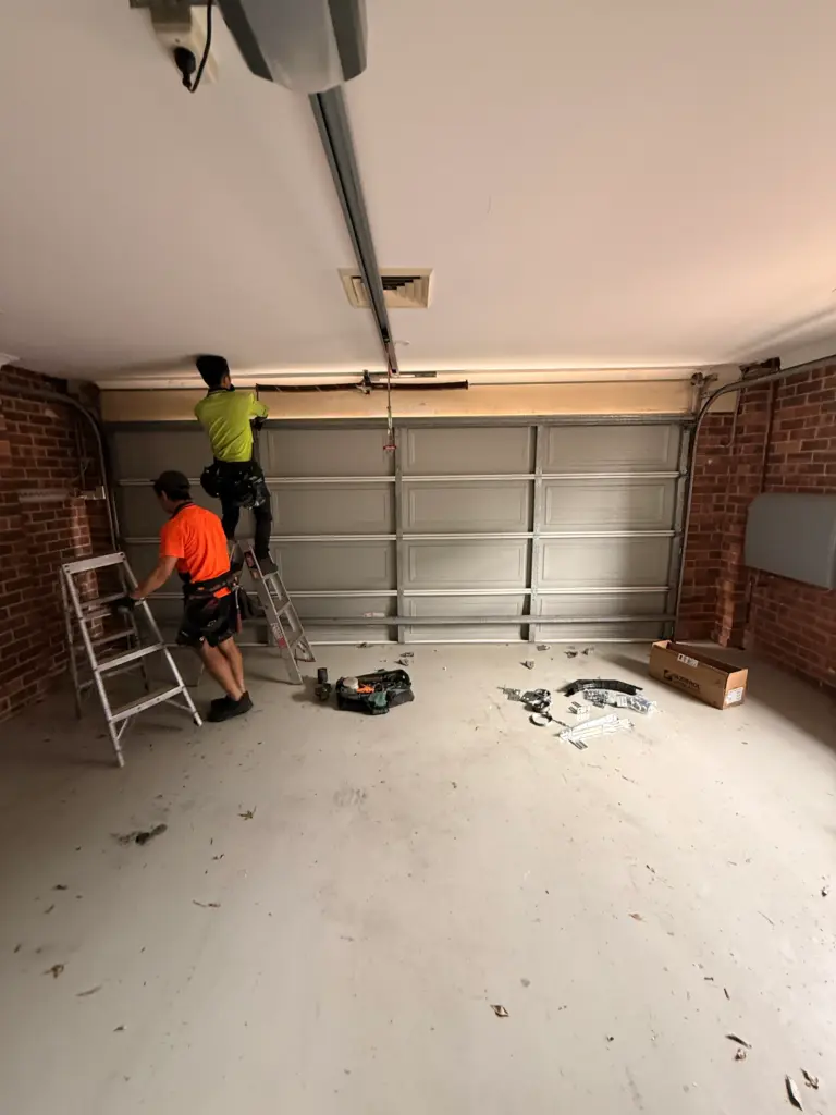 Two technicians installing a sectional garage door