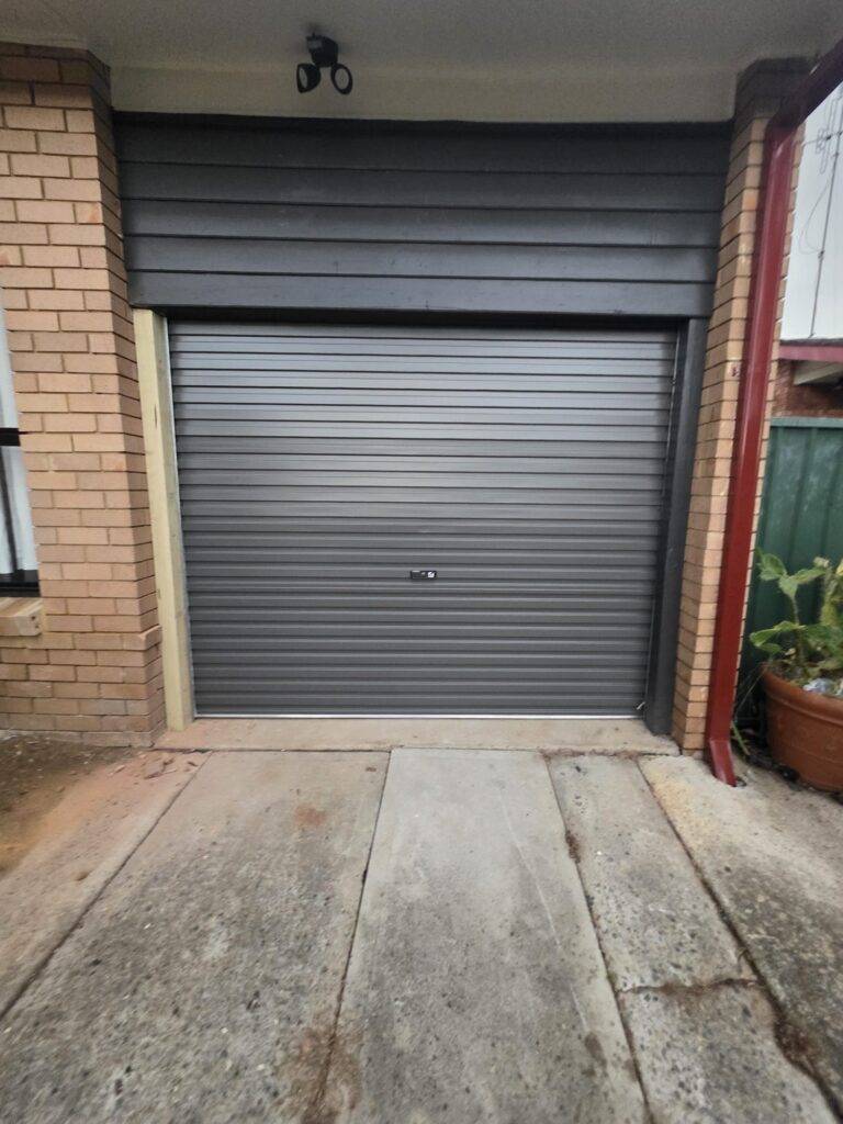 Charcoal roller garage door installed in a brick garage