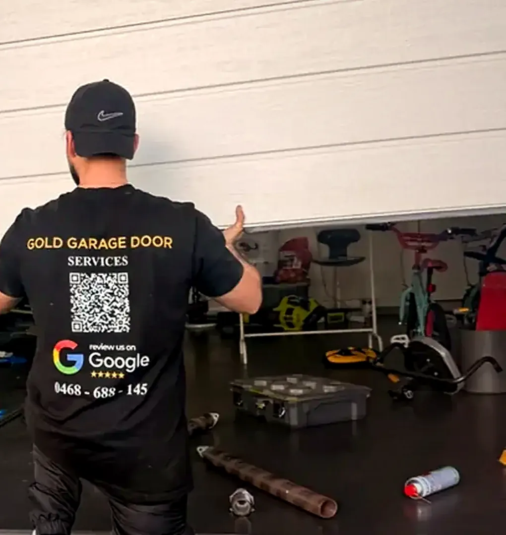 Gold Garage Door technician lifting a sectional garage door during a repair in Sydney